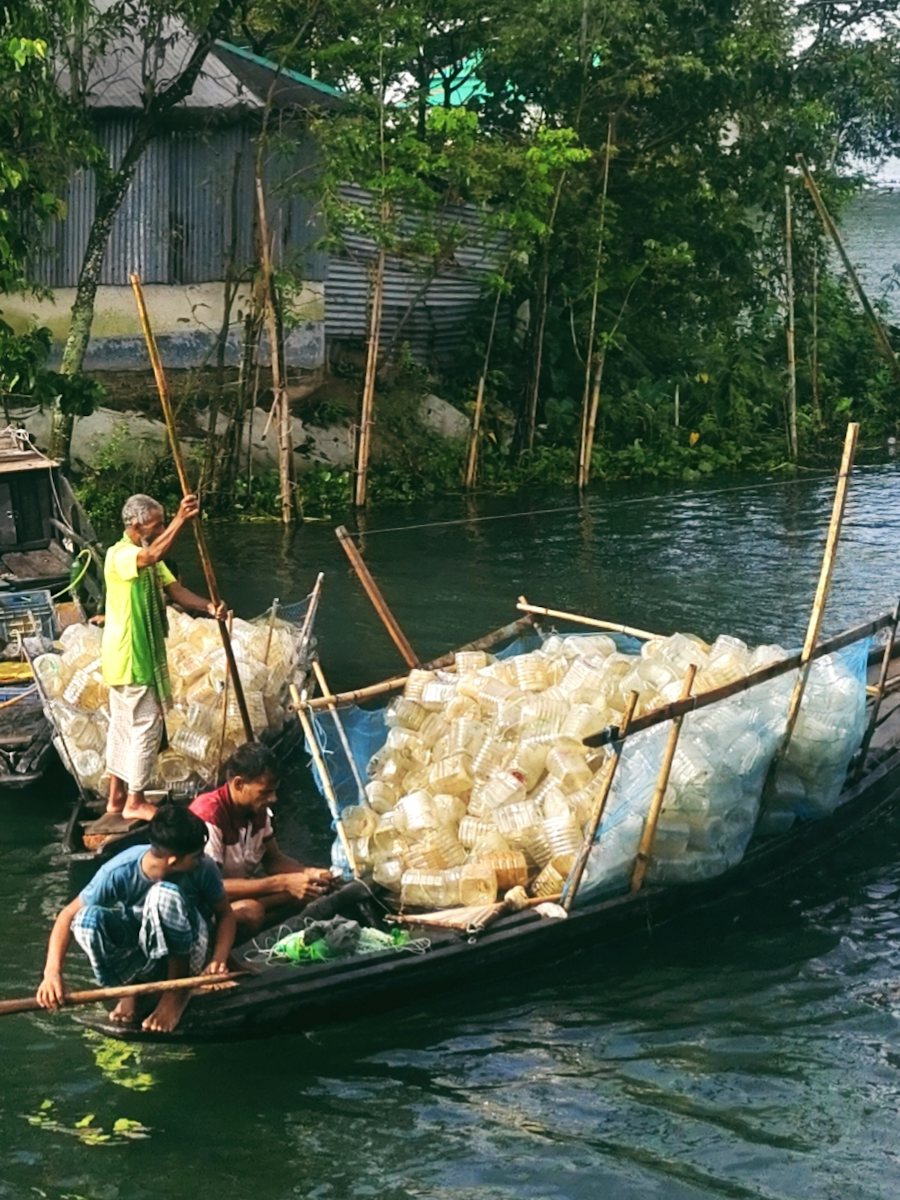 Villagers in wooden boats on a river beside stilt houses